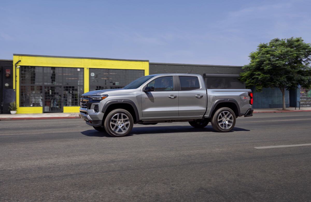 A gray 2023 Chevrolet Chevy Colorado Z71 midsize pickup truck model driving past a yellow building