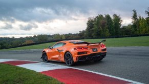 A bright orange 2023 Chevrolet Corvette Z06 corners hard on a racetrack.