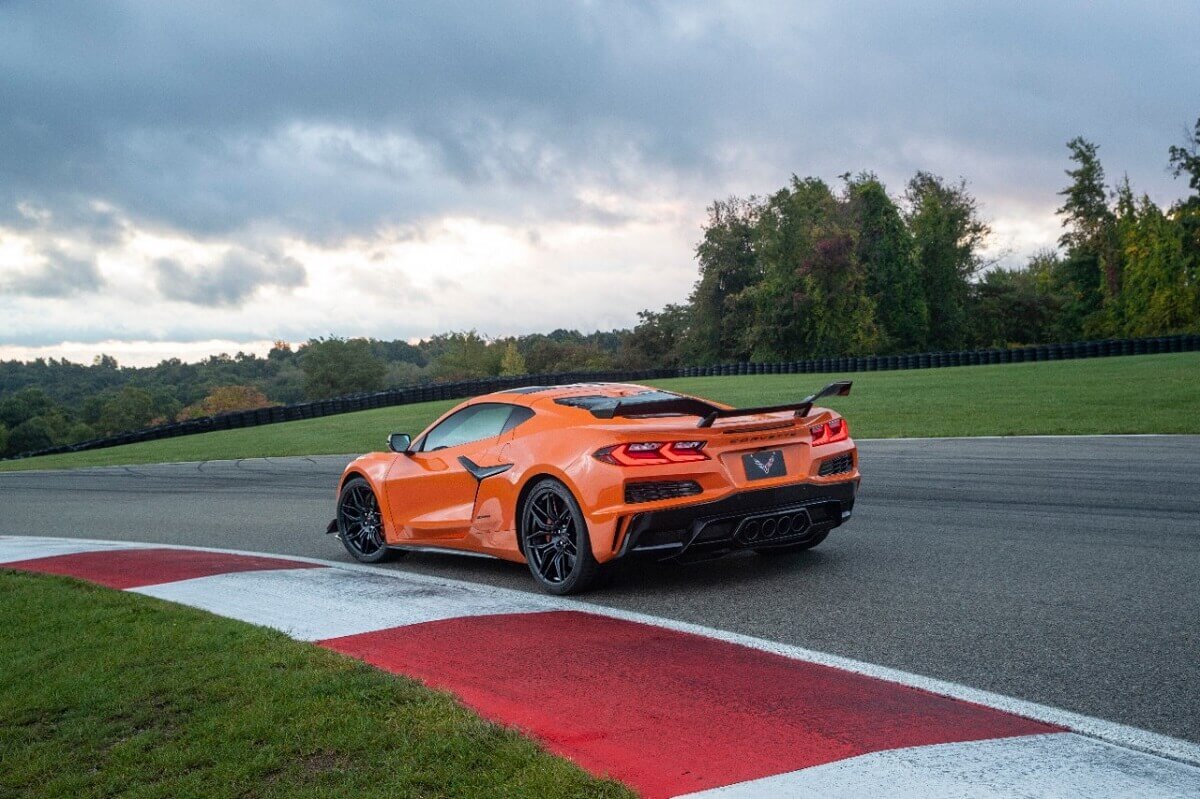 A bright orange 2023 Chevrolet Corvette Z06 corners hard on a racetrack. 