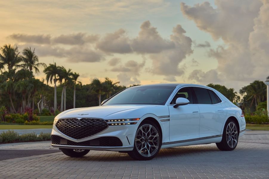 A white 2023 Genesis G90 in front of some palm trees.