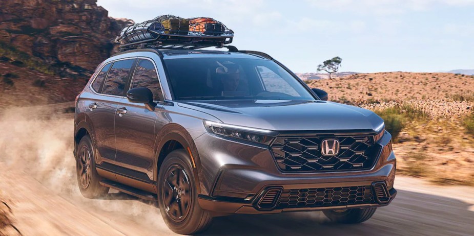 A gray 2023 Honda CR-V Hybrid small hybrid SUV is driving off-road. 