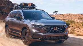 A gray 2023 Honda CR-V Hybrid small hybrid SUV is driving off-road. It's definitely not the best Honda of 2023.