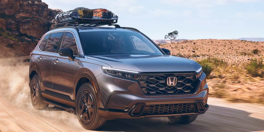 A gray 2023 Honda CR-V Hybrid small hybrid SUV is driving off-road. It's definitely not the best Honda of 2023.