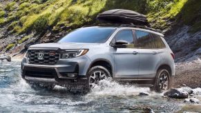 A gray 2023 Honda Passport midsize SUV is driving off-road.