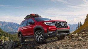 A red 2023 Honda Passport midsize SUV is driving off-road.