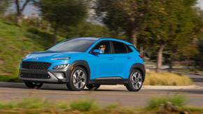 A light blue 2023 Hyundai Kona driving outdoors.