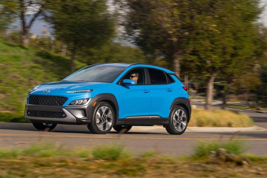 A light blue 2023 Hyundai Kona driving outdoors.