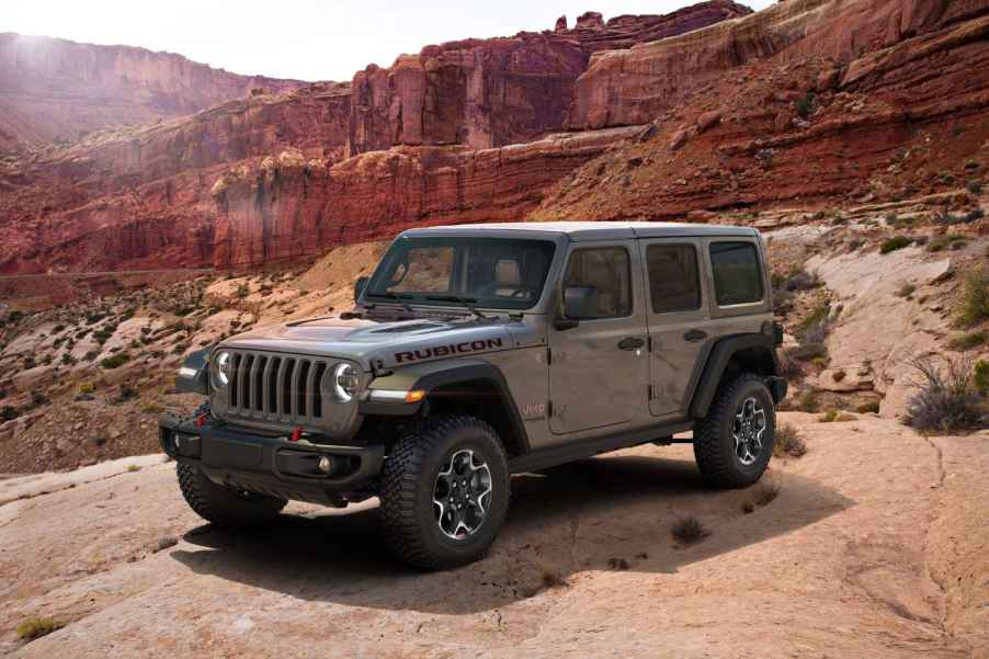 A 2023 Jeep Wrangler Rubicon scales red rocks in the desert. It's rated as one of the most reliable American SUVs of 2023.