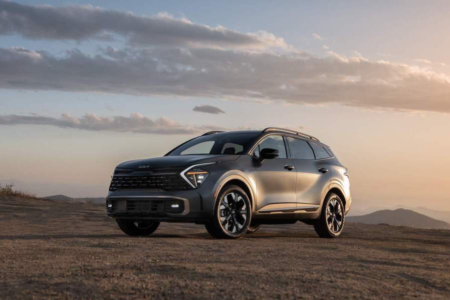 A silver 2023 Kia Sportage Hybrid parked on flat land in front of a cloudy sky.