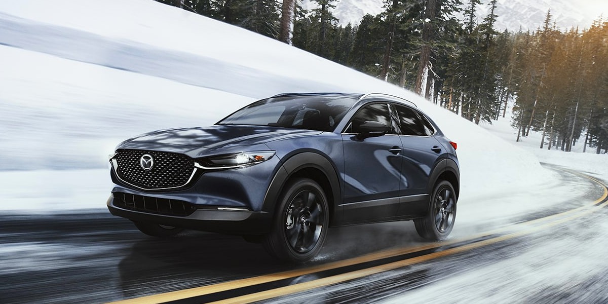 A 2023 Mazda CX-30 driving down a snowy road.