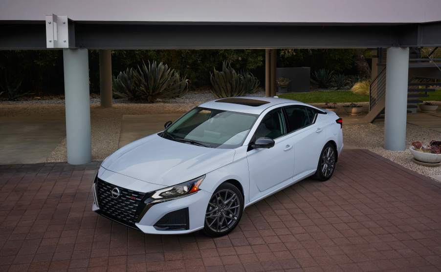 A white 2023 Nissan Altima parked in front of a building.