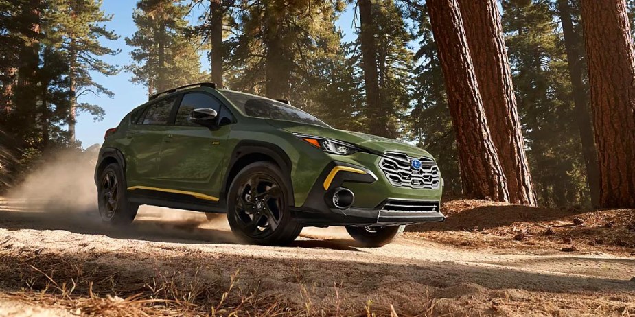 A green 2024 Subaru Crosstrek subcompact SUV is driving off-road. 