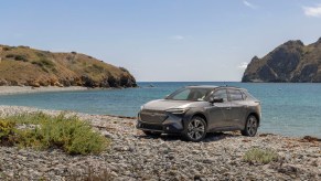 A silver 2023 Subaru Solterra parked in front of a body of water. The Solterra is the most disappointing 2023 Subaru model.