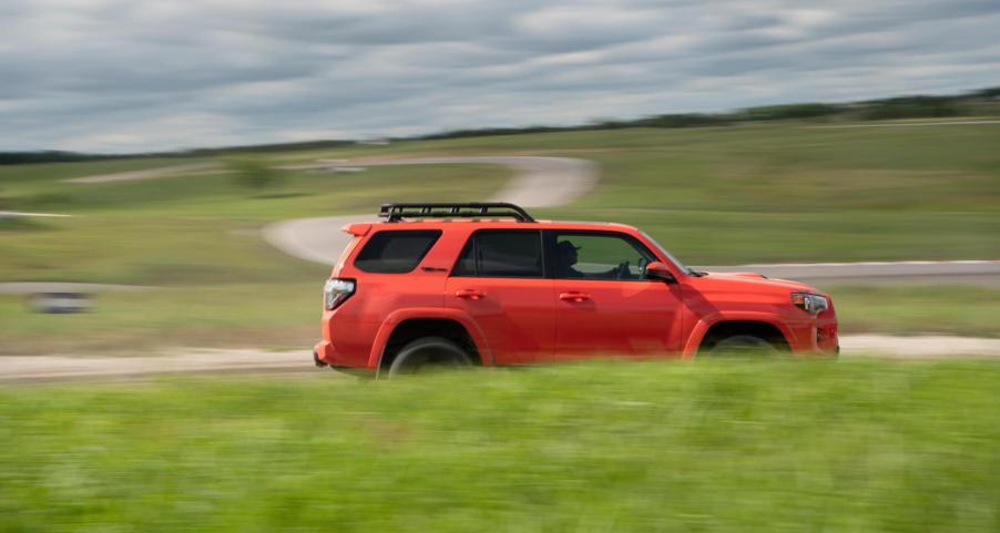 An orange Toyota 4Runner TRD Pro drives at speed with a blurry foreground and background of green grass.