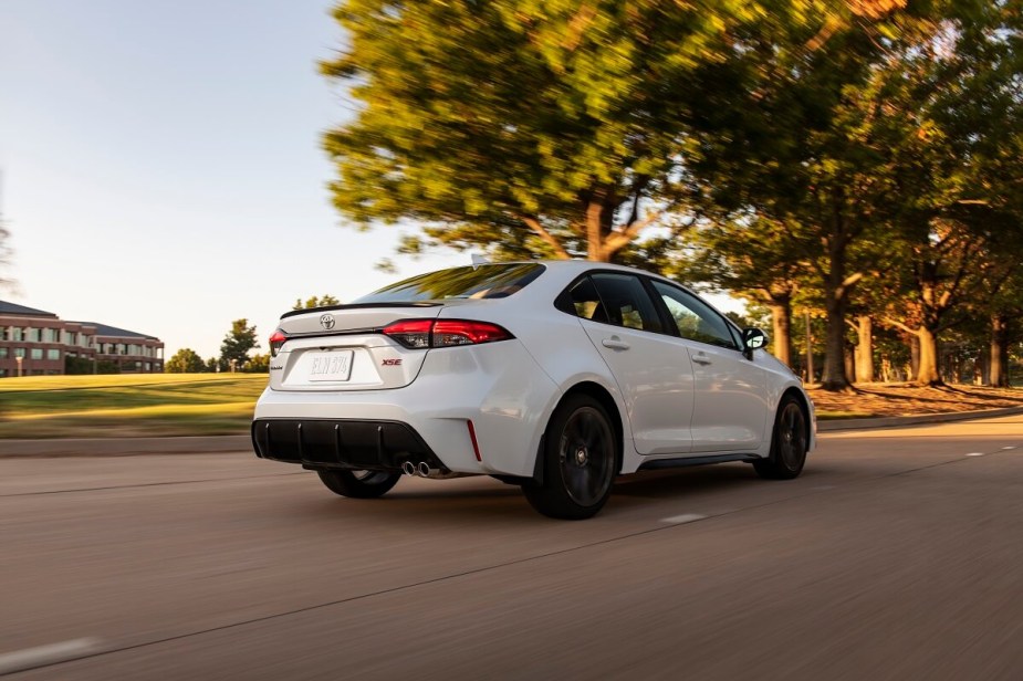 A white 2023 Toyota Corolla car cruises a country road. 