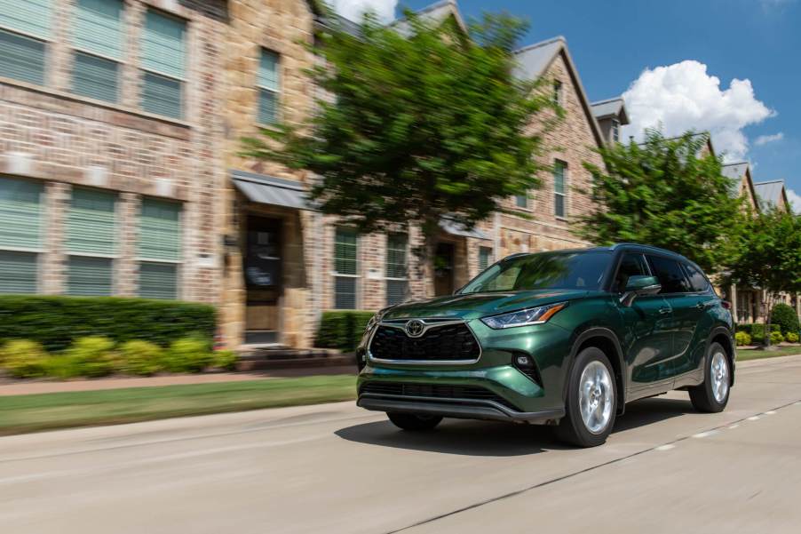 A green Toyota Highlander drives in front of a limestone building.