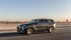 A 2023 Hyundai Palisade SUV cruises through the desert in twilight.