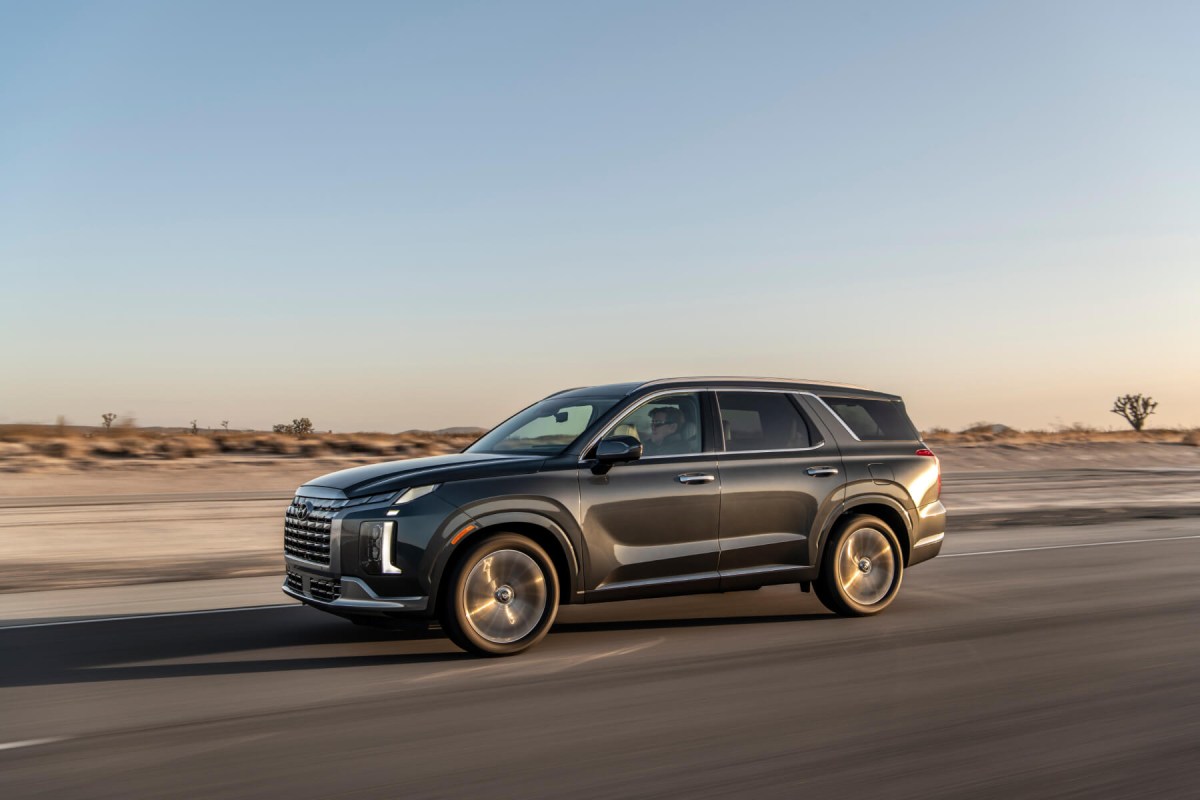 A 2023 Hyundai Palisade SUV cruises through the desert in twilight.