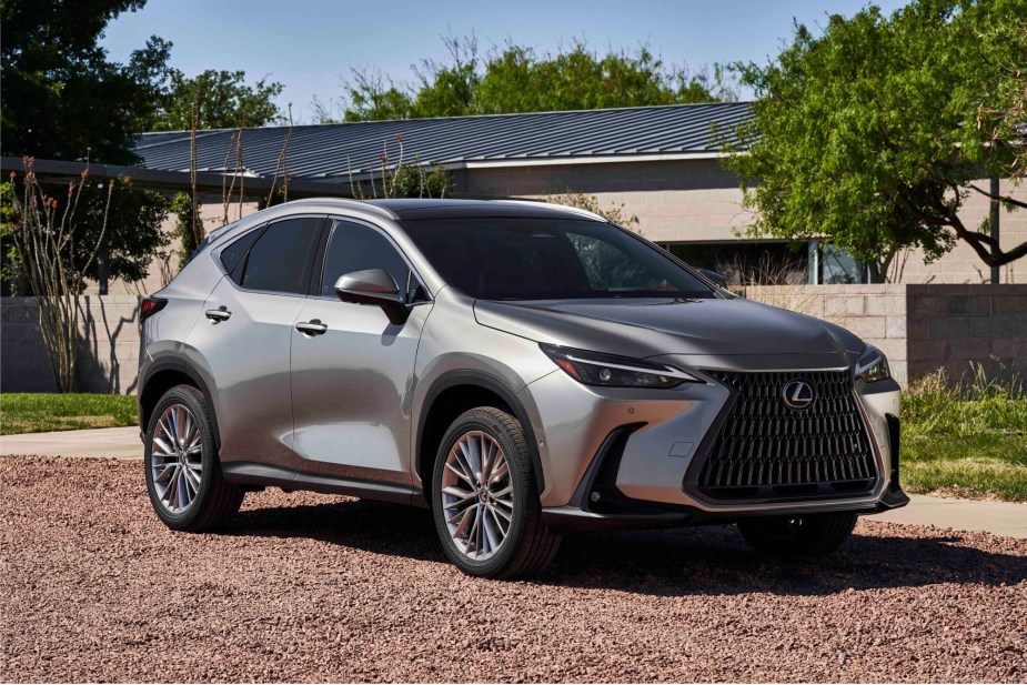 A silver Lexus RX sits on a pebble driveway in front of a home in midday sun. 