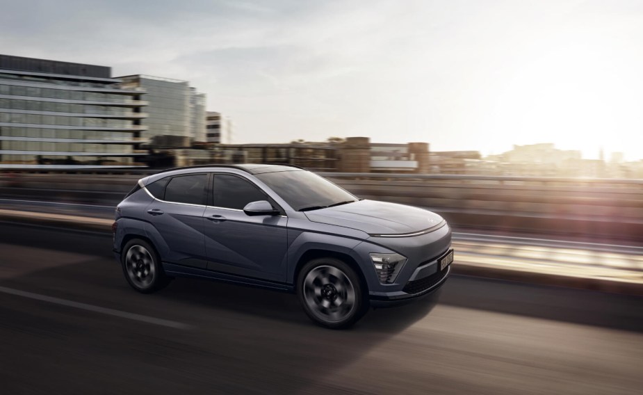 Side view of a new 2024 Hyundai Kona driving on a highway at sunset.  