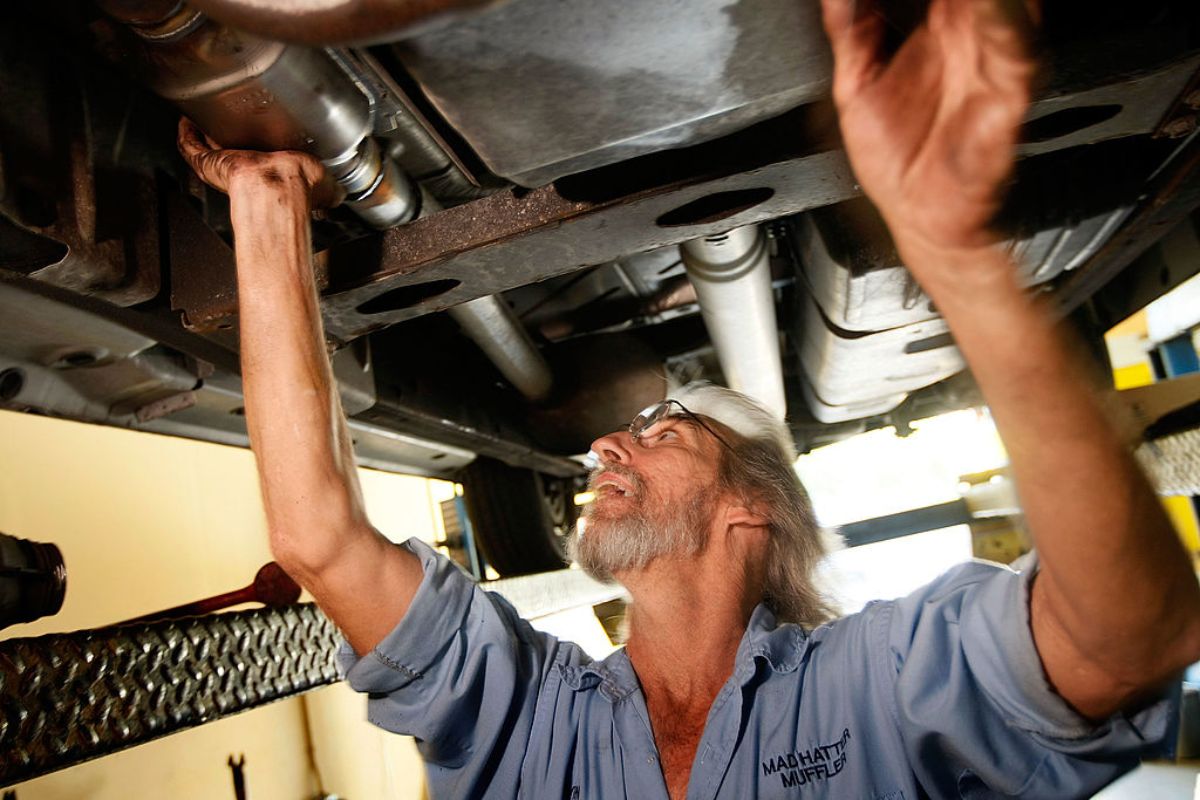 A mechanic working on a cars catalytic converter.