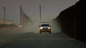 border patrol vehicle driving along a fence line