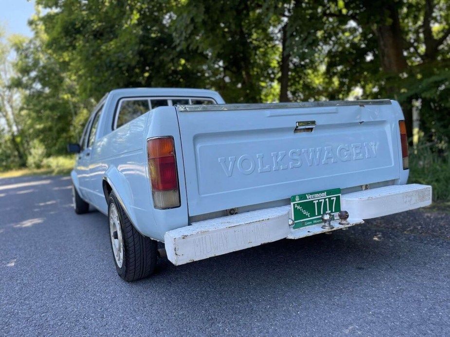 The tailgate of a blue Rabbit pickup truck, with the word Volkswagen visible, and trees in the background.