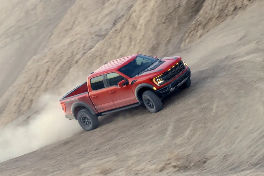 A 2023 Ford F-150 Raptor drives through the sand as a full-size truck.