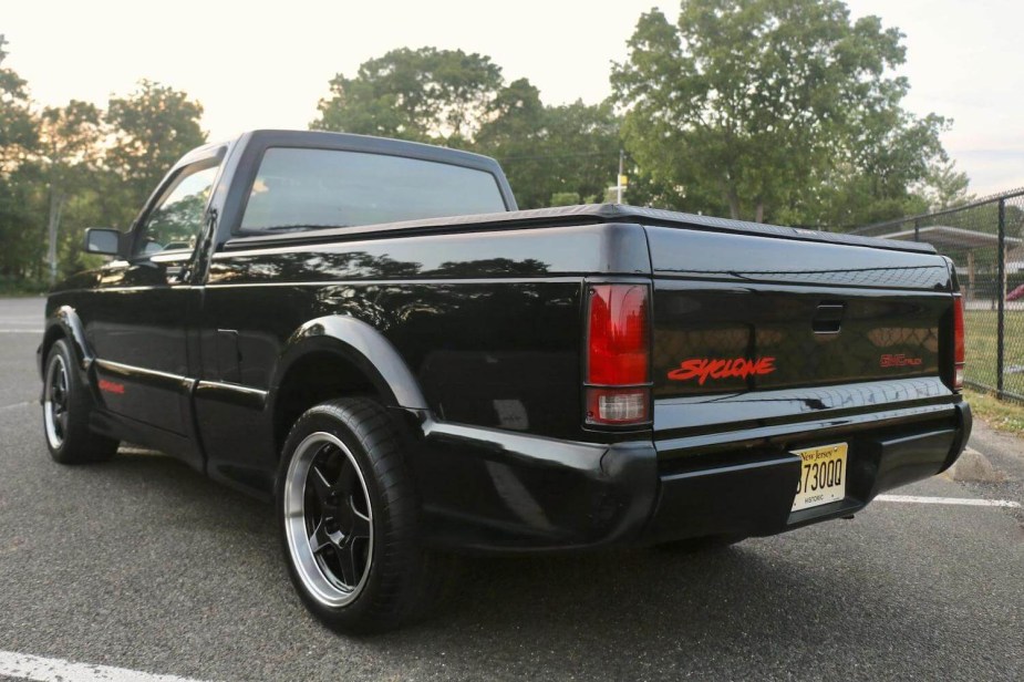 The tailgate of a GMC supertruck with the word "Syclone" in red paint, trees visible in the background.