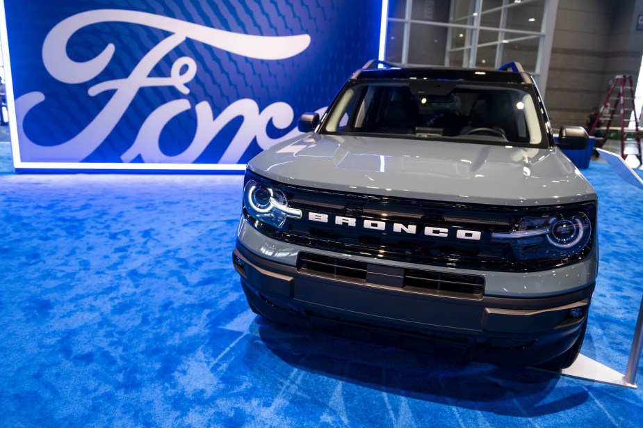 Front-on view of grey Ford Bronco Sport in front of a large Ford logo set on blue carpet.