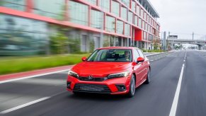 A small, red 2022 Honda Civic blasts down a safe city street away from other cars.