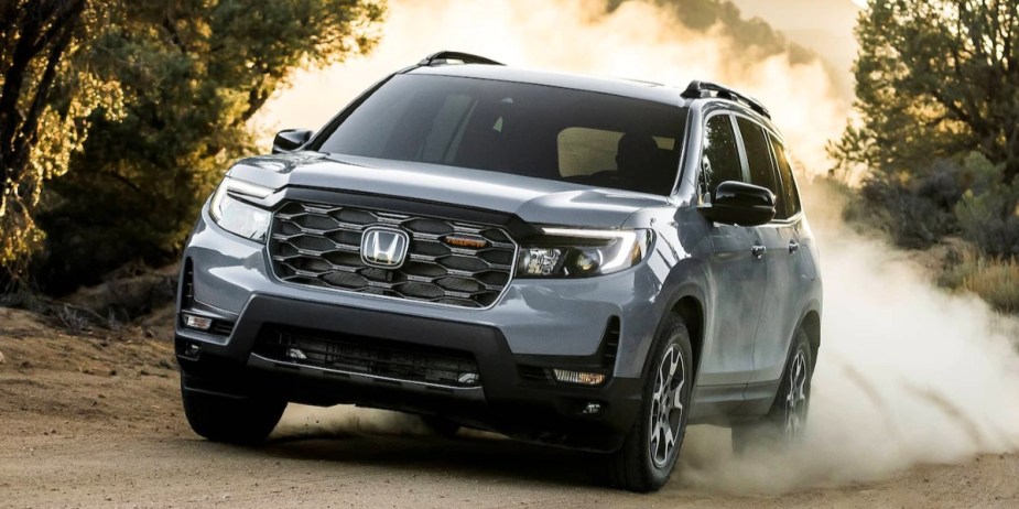 A gray 2023 Honda Passport midsize SUV is driving off-road. 