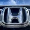 A silver Honda logo on a grille with a blue sky in the background. Honda vs. Hyundai is a debate that basically has two winners.