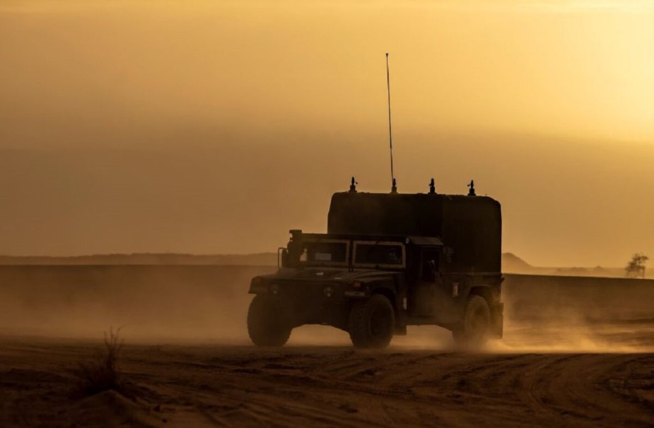 A surplus Humvee military vehicle drives through an African desert. 