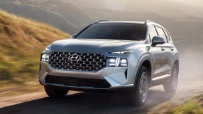 A gray 2023 Hyundai Santa Fe Plug-In Hybrid small hybrid SUV is driving off-road.