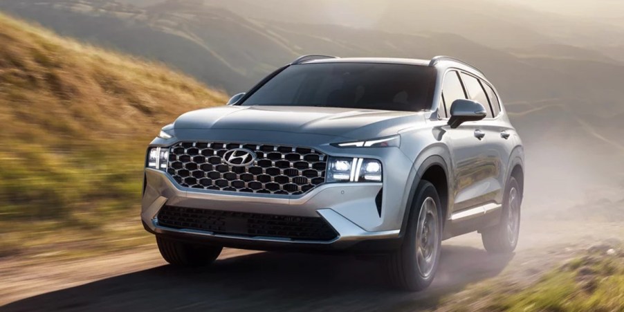 A gray 2023 Hyundai Santa Fe Plug-In Hybrid small hybrid SUV is driving off-road.