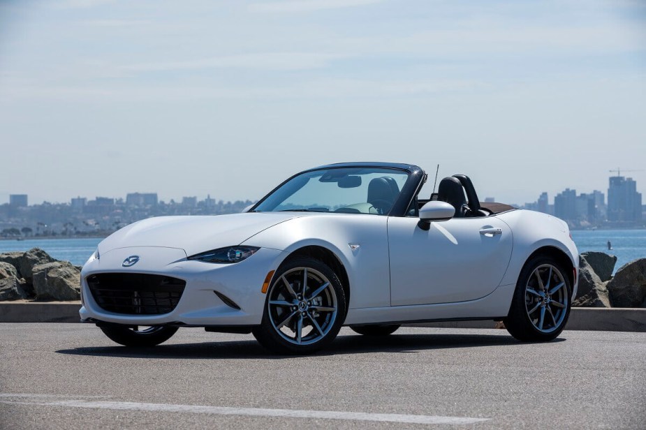 A white 2023 Mazda MX-5 Miata sports car shows off its convertible top. 