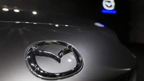 A Mazda logo on a Mazda MX-5, one of the top Mazda models, with a blurred Mazda logo in the background.