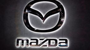 A backlight Mazda logo hanging on a wall.