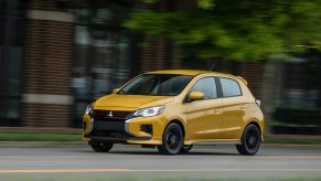 A Mitsubishi Mirage hatchback driving down the road.