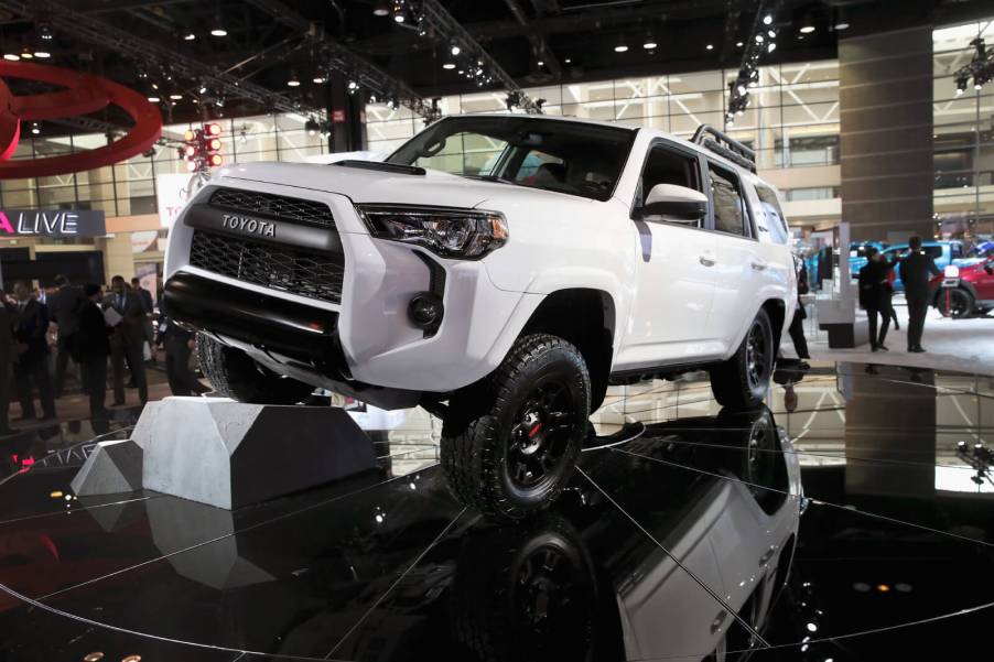 A new Toyota 4Runner in white propping up one wheel on a black floor at an auto show.