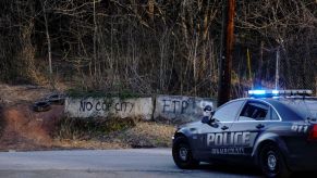 Police car stopped in front of a sign saying "No Cop City"