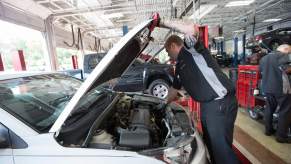 A person potentially performing a recall repair on a white car.