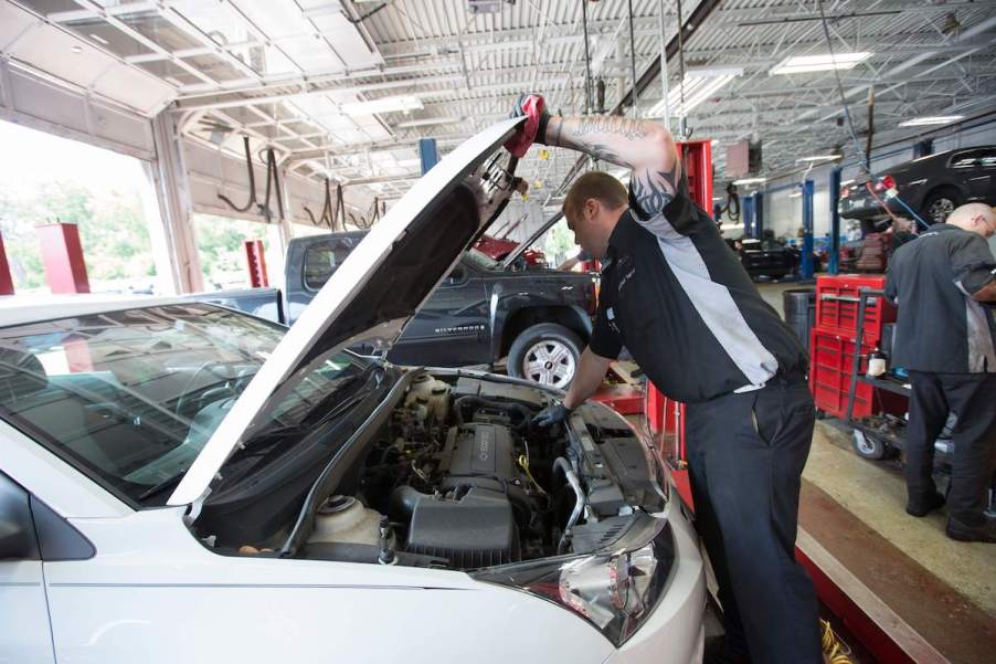 A person potentially performing a recall repair on a white car.