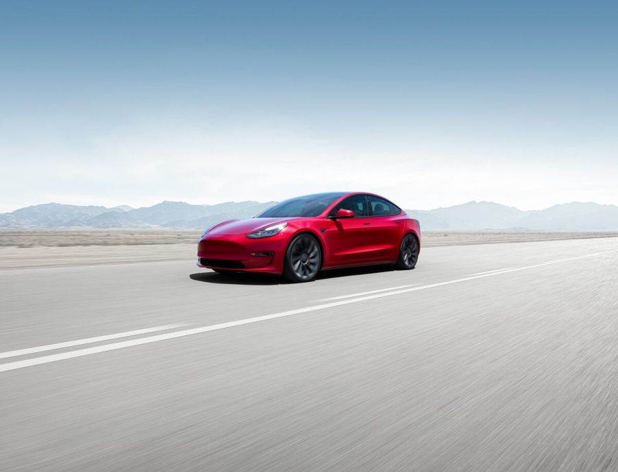 A red 2023 Tesla Model 3 blasts down an open road at speed, buoyed by its top safety scores.