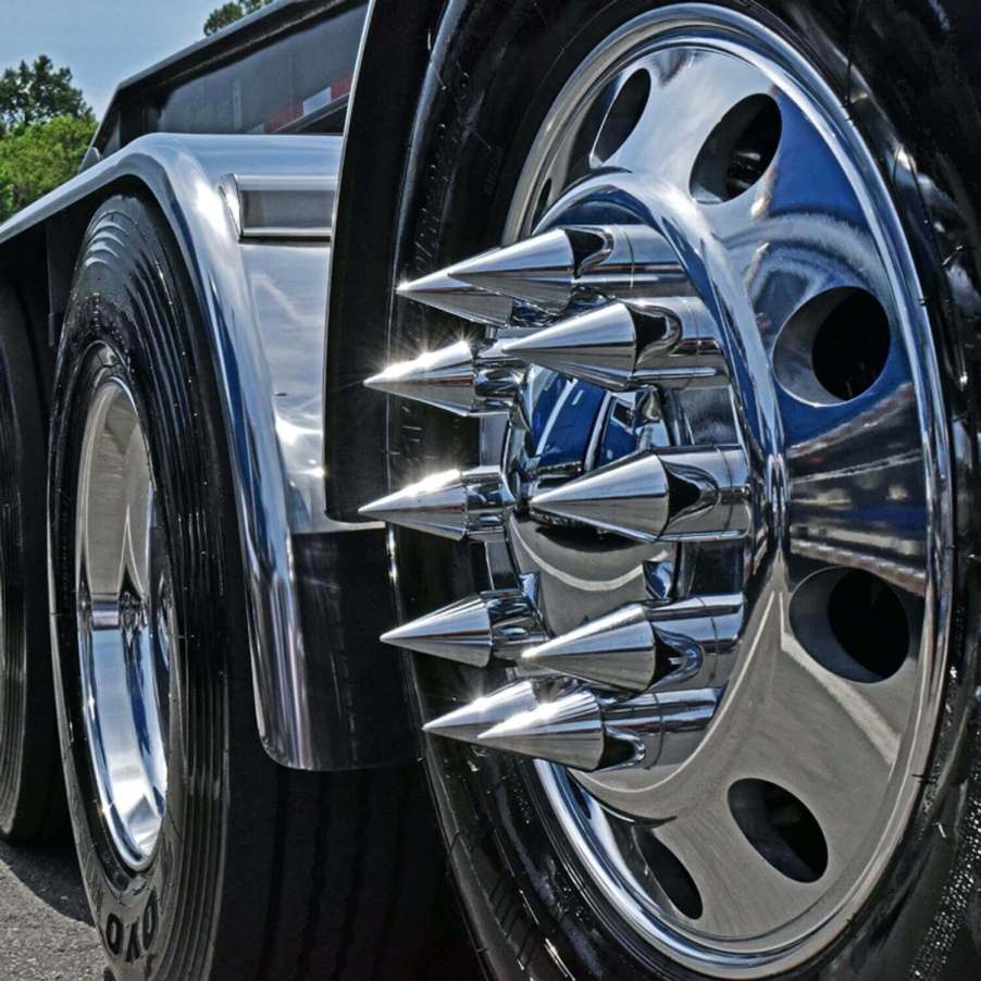 Closeup of the chromed lug nut cover spikes on the wheel of a semi truck.