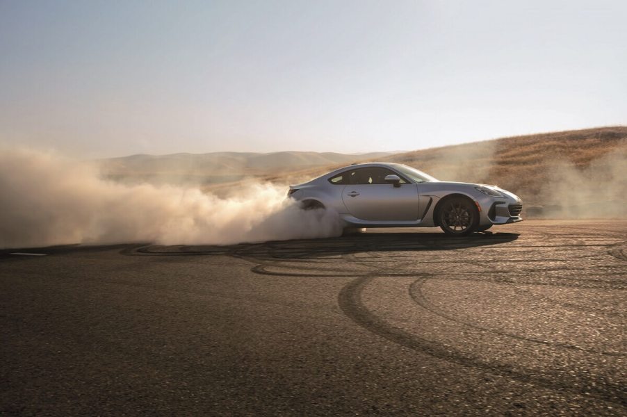 A 2023 Subaru BRZ sports car shows off its silver paintwork as it safely drifts on the sandy tarmac.