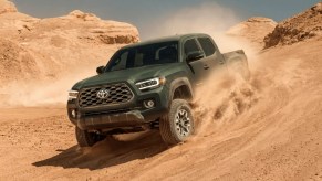 A Toyota Tacoma midsize truck is driving through the sand.