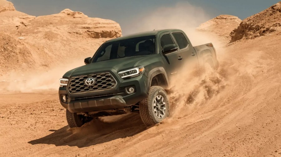 The 2023 Toyota Tacoma midsize truck drives through sand.