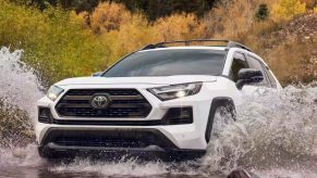 A white 2023 Toyota RAV4 small SUV is driving off-road.